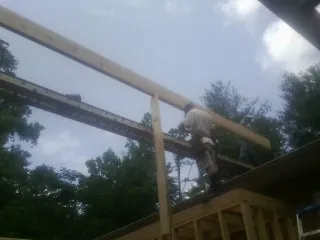 Carpenter setting a ridge beam over a new addition frame — Ice Dam Removal by Roofing Brothers in Goodrich
