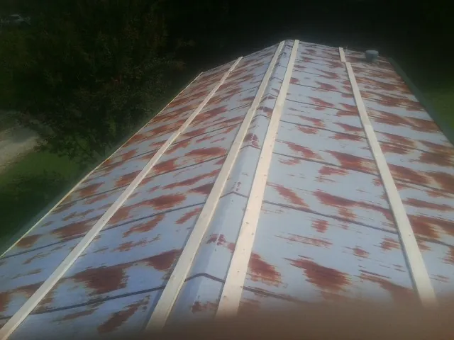 Rusted metal roof panels with new wood purlins before replacement — Storm Damage Roof Repair in Goodrich by Roofing Brothers