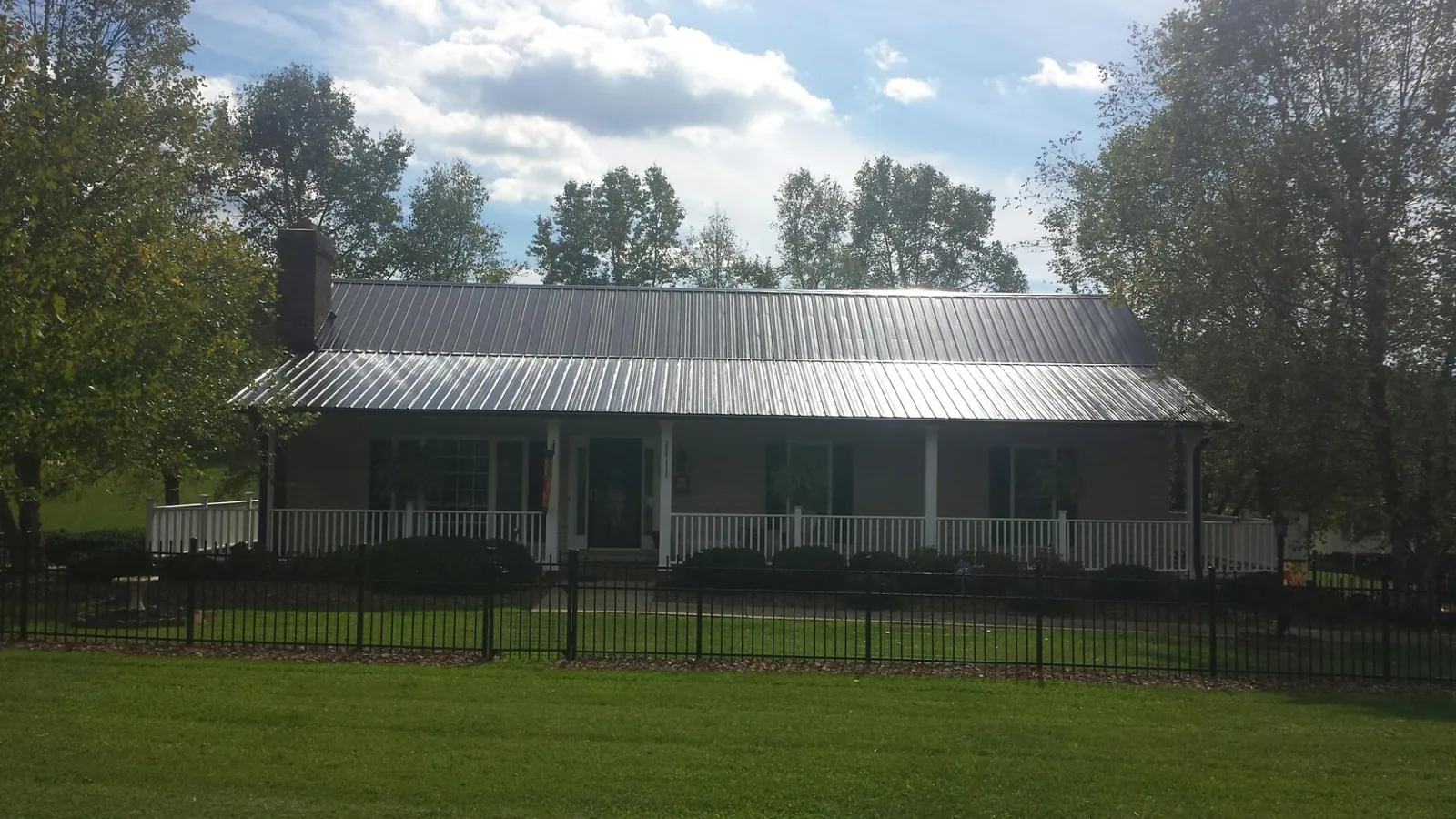Gray metal roof on a brick ranch with a full width front porch — Gutter Guard Installation work by our crew in Goodrich